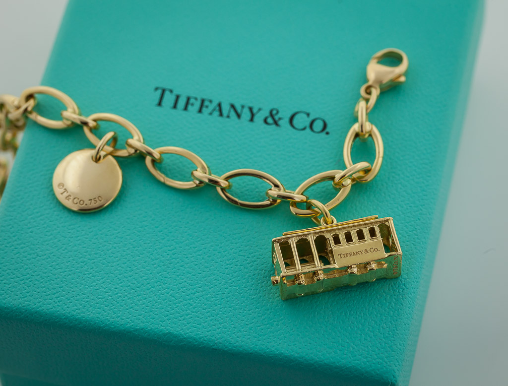 Sold at Auction: TIFFANY 18KT GOLD CHARM BRACELET - ETOILE DIAMOND HEART -  JEWELED SUITCASE - ANGEL CHERUB - MOP OYSTER CHARM